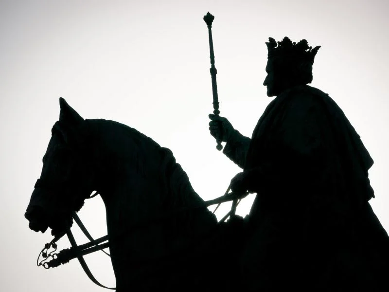 silhouette of a king riding on a horse holding a scepter