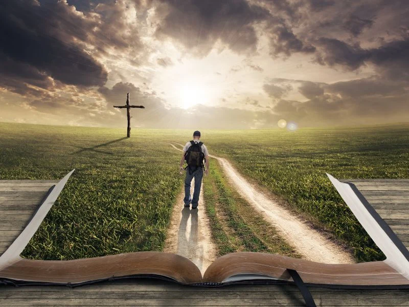 Man with a backpack walking on a road formed from the Bible