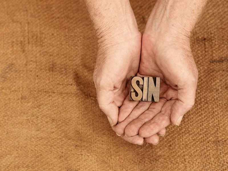 a woman holding the word sin in her hands