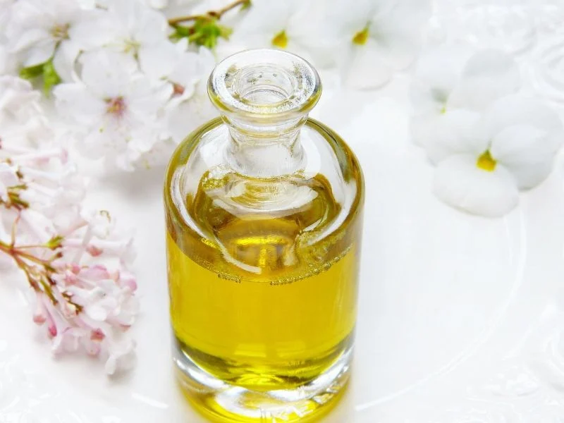 a small bottle of oil surrounded by white flowers