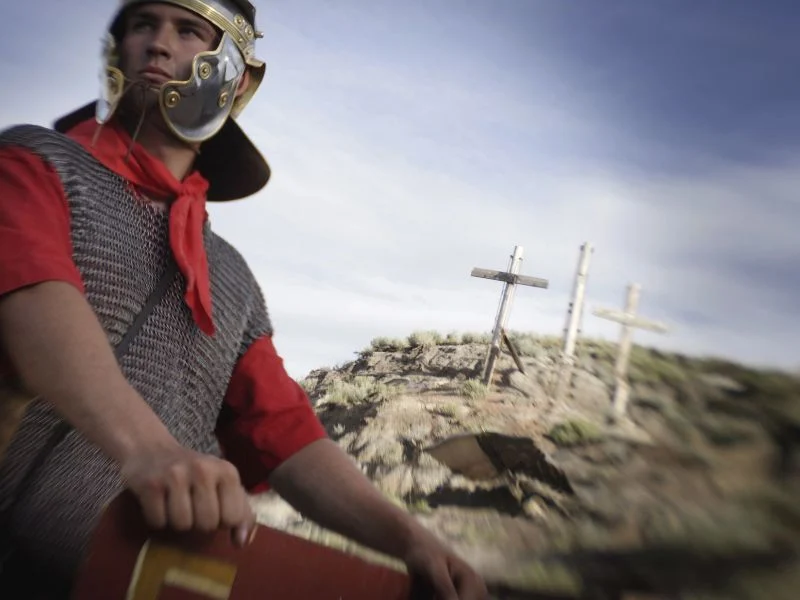 A roman soldier standing in front of three crosses on a hill