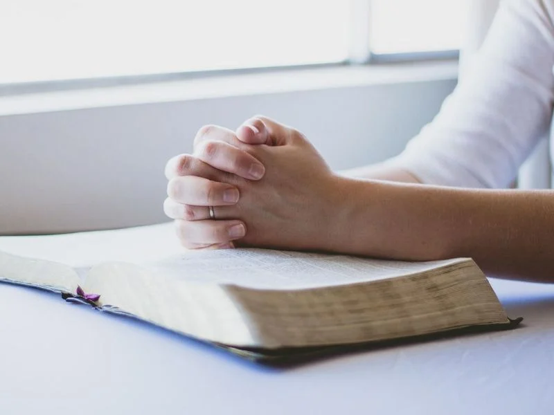 Woman praying to God with an open Bible