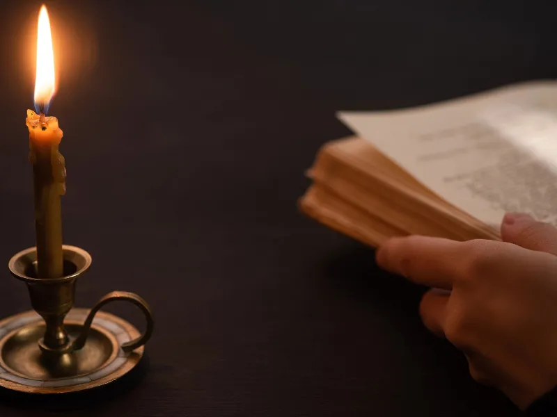 Bible on a table near an antique candle
